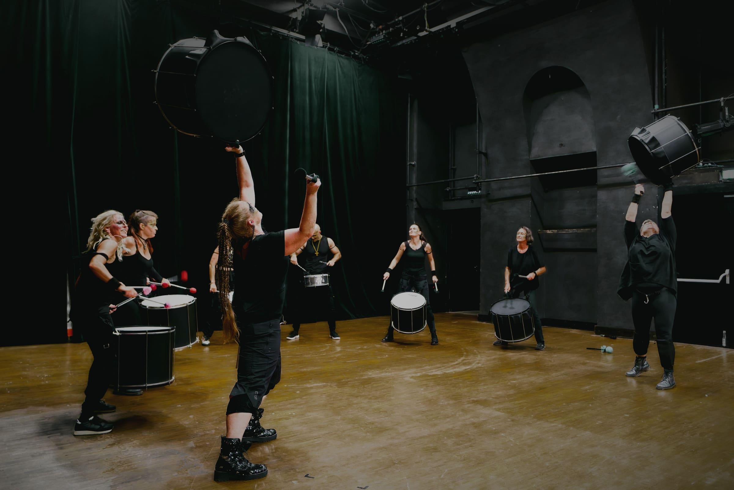 SUCAREDO bei der Premiere im Museumsquartier: Vorne reißt jemand die große Surdo über den Kopf, dahinter spielt die Band auf der dunklen Bühne.